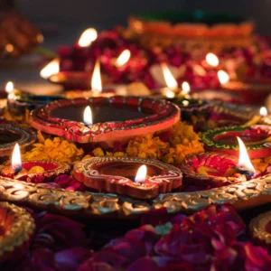 Lit clay diyas on a decorative tray surrounded by flower petals